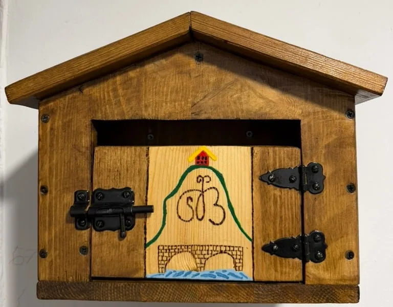 El buzón de las cartas, con La Higa y el puente pintados en la puerta
